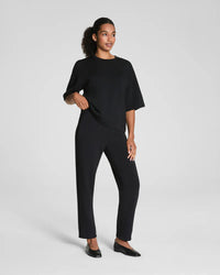 Full length view of black stretch tapered pants paired with flats