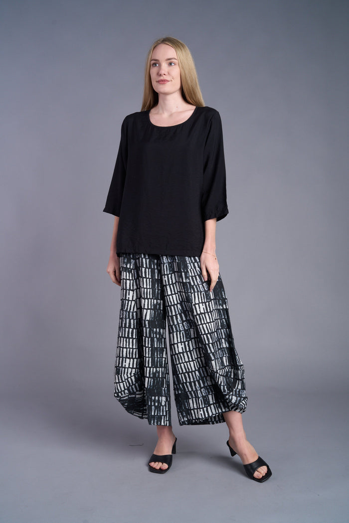 Woman modeling a black 3/4 sleeve blouse with patterned wide-leg pants