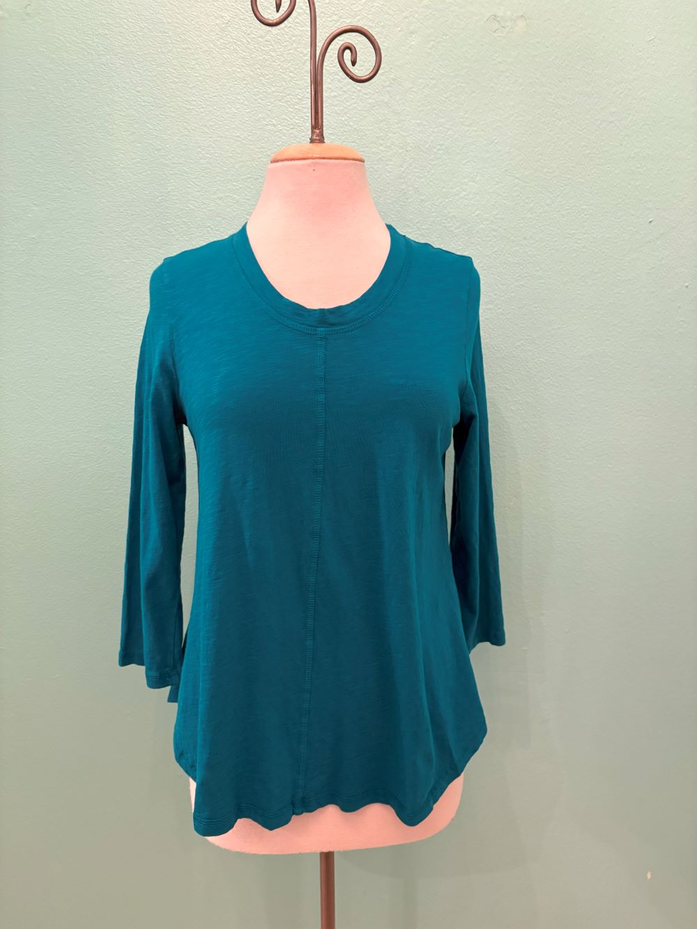 Front view of a teal 3/4 sleeve women's top on a mannequin against a light background