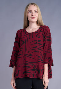 Close-up of woman wearing a burgundy tunic top with a black abstract print and 3/4 sleeves