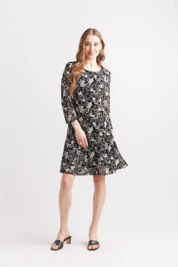 Woman wearing a black floral swing dress with 3/4 sleeves and black heeled sandals