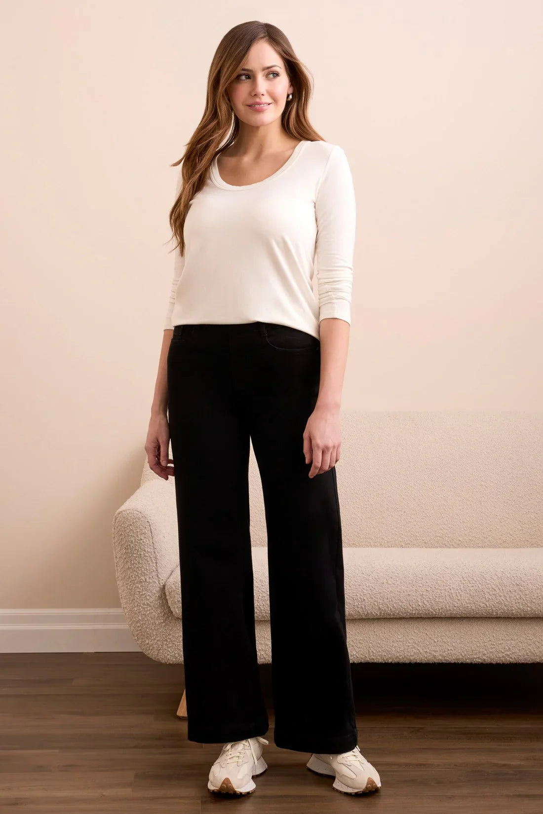 Three-quarter view of a woman in stylish black wide-leg pants and casual sneakers