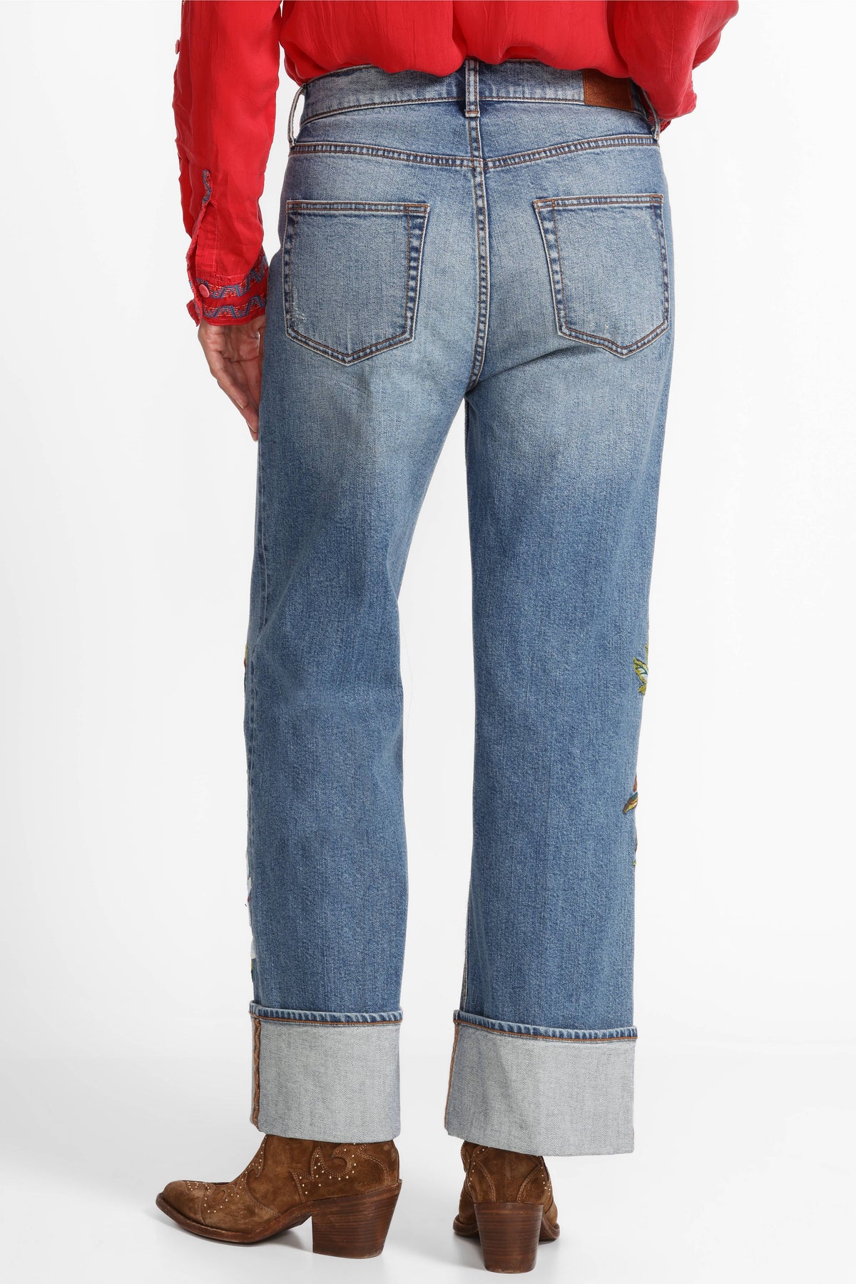 Back view of wide-leg jeans with large cuffs and minimal embroidery, paired with western boots