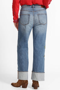 Back view of wide-leg jeans with large cuffs and minimal embroidery, paired with western boots