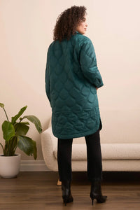Back view of a woman wearing an evergreen quilted longline jacket, styled with black pants and boots.