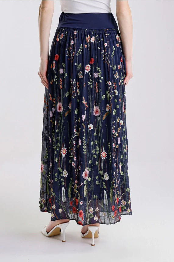 Back view of navy floral embroidered maxi skirt, styled with white heels