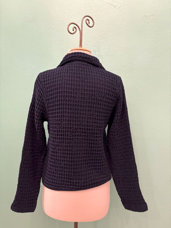 Back view of a navy waffle knit button-up cardigan on a mannequin