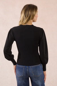 Back view of black mesh detail sweater paired with blue jeans