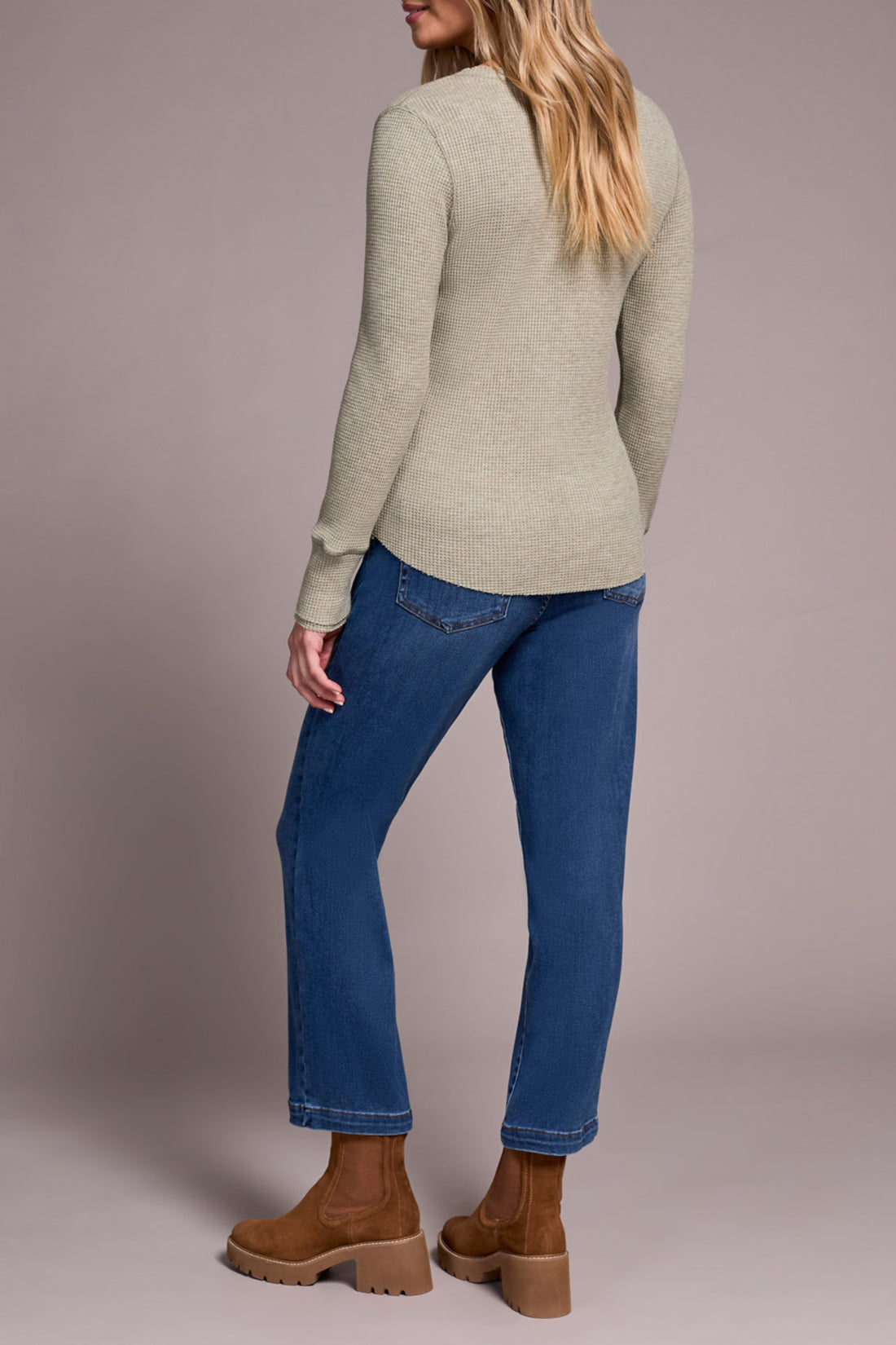Back view of woman wearing straight-leg blue denim jeans with tan boots