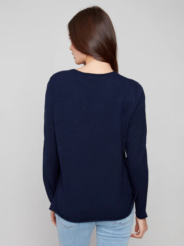 Back view of woman wearing a classic navy v-neck sweater with light blue jeans