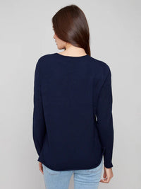 Back view of woman wearing a classic navy v-neck sweater with light blue jeans
