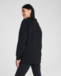 Rear view of woman showcasing the length and fit of a black pullover