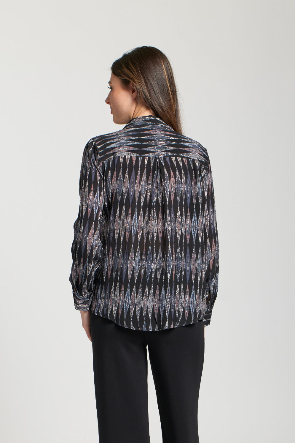 Back view of a woman wearing a black blouse with an all-over metallic diamond pattern