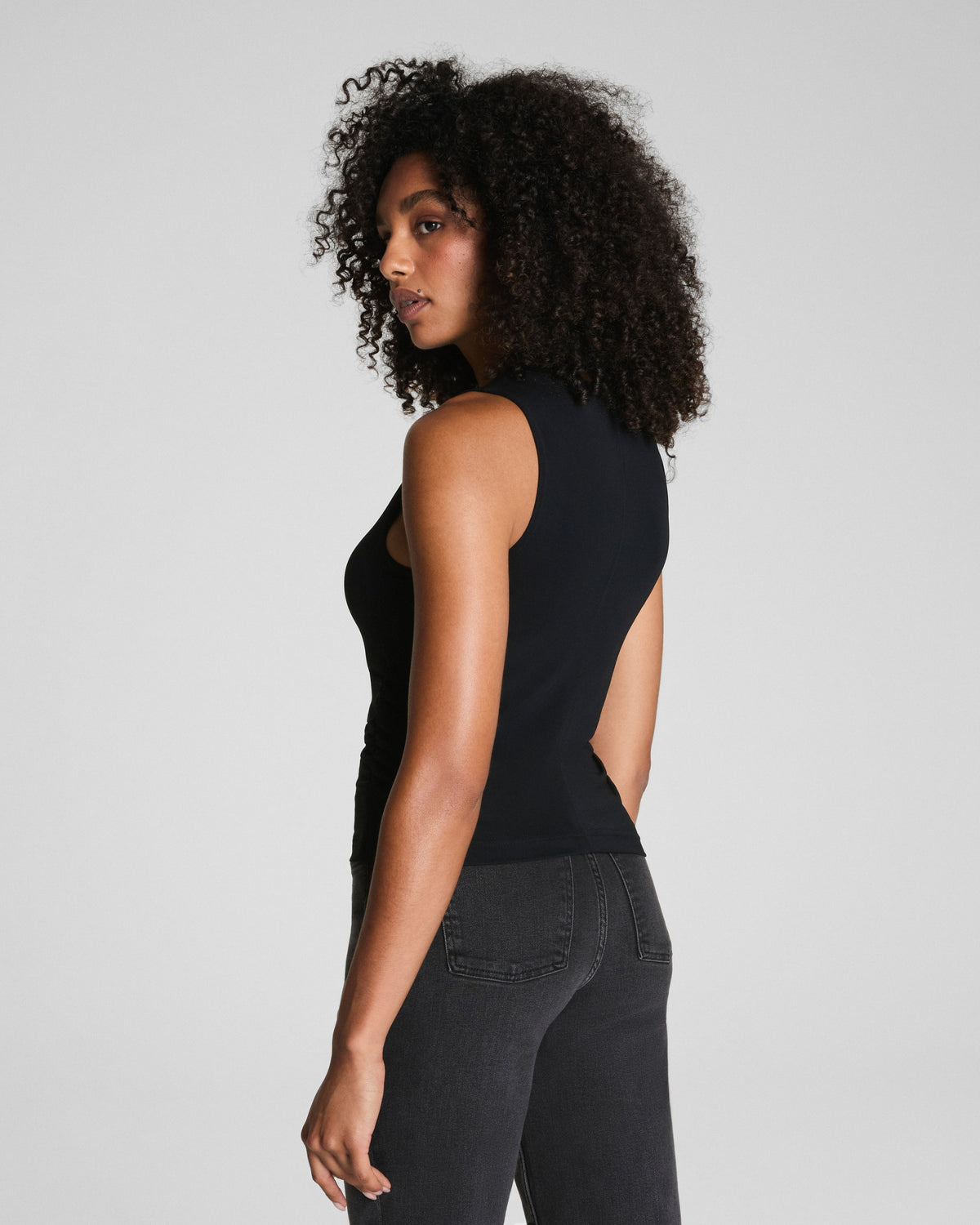 Back angle of black ruched tank top paired with dark high-waist jeans