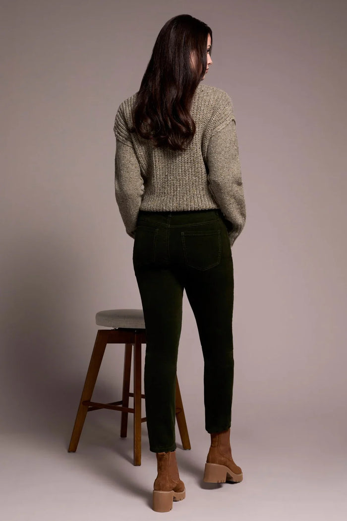 Back view of a woman wearing olive green corduroy pants and a knitted sweater