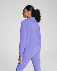Back view of a woman in a matching violet zip-up jacket and leggings set