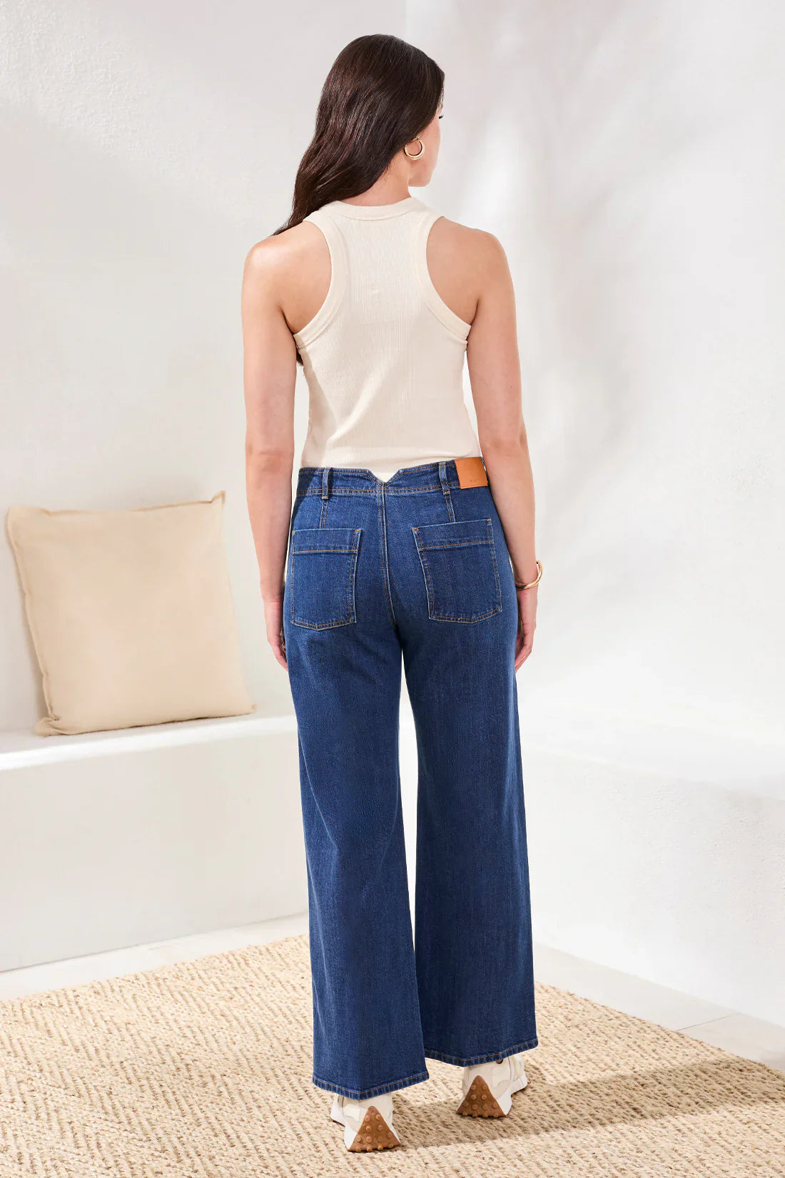 Back view of model wearing wide-leg blue denim jeans with a white top