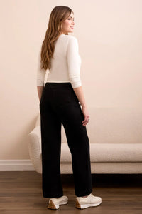 Back view of a woman wearing black wide-leg pants paired with a white top