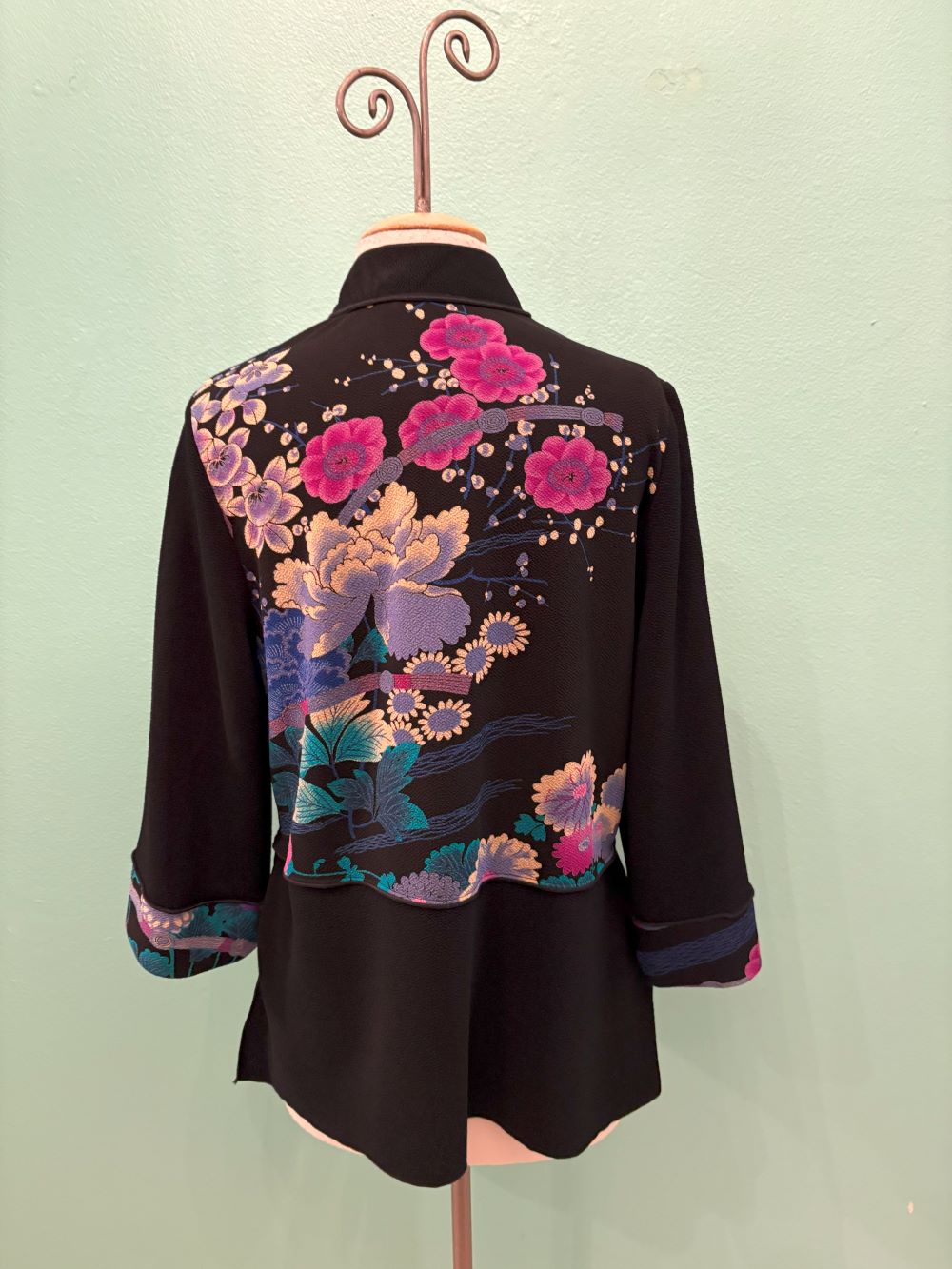 Back view of black Asian-inspired jacket with vibrant pink and purple floral embroidery