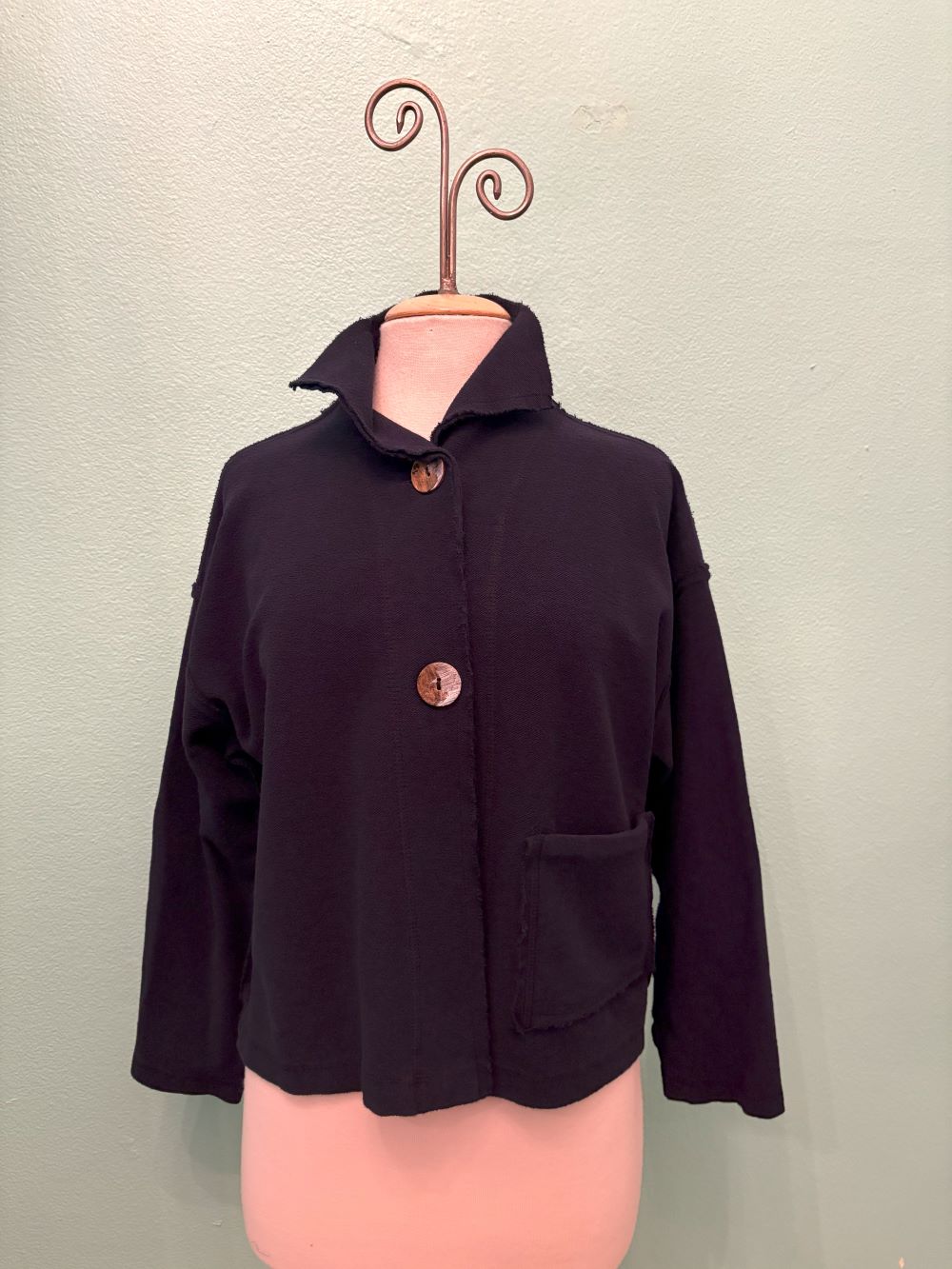 Full front view of black cropped button-up jacket with pocket and collar