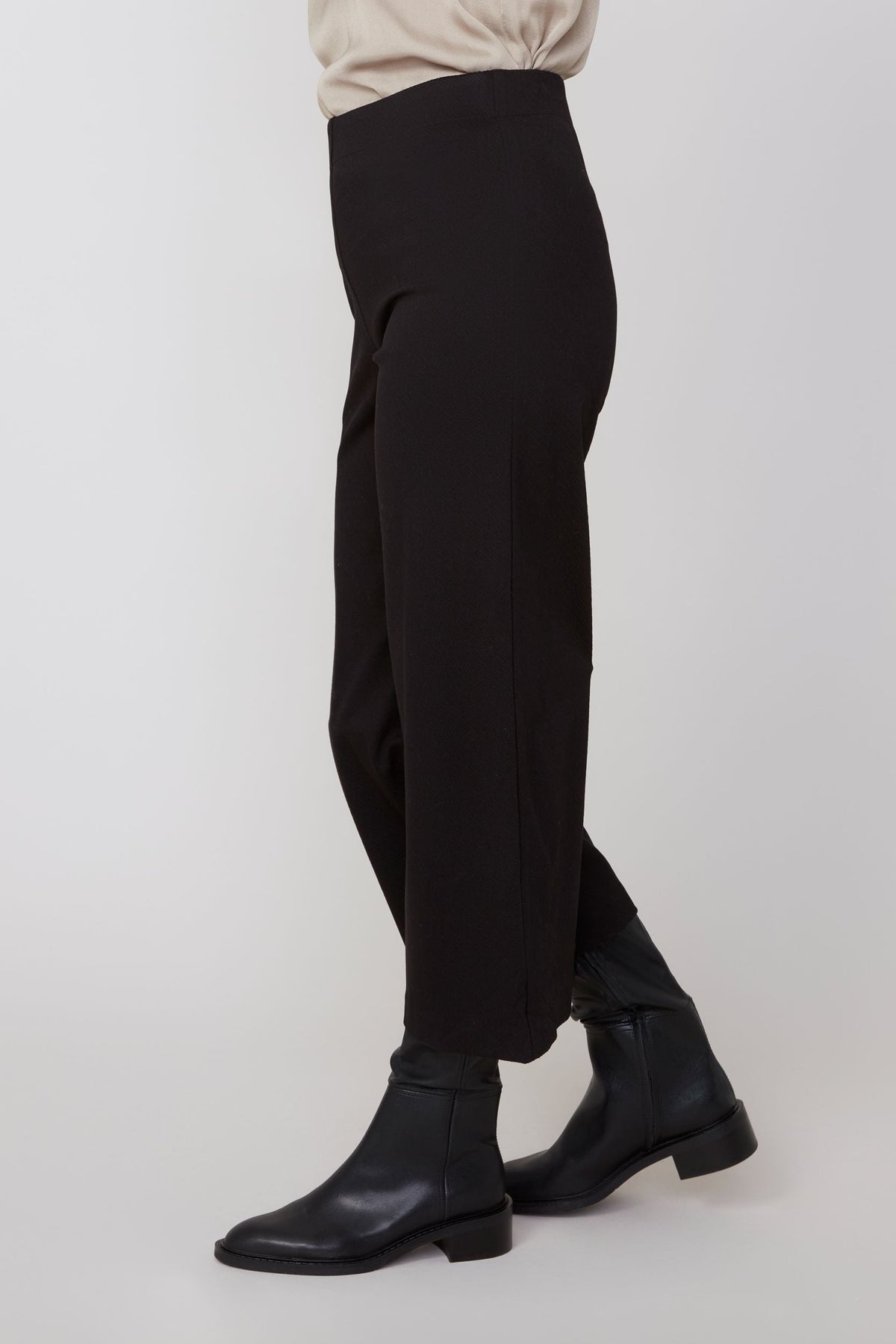 Side profile showcasing the relaxed fit and ankle length of black cropped pants