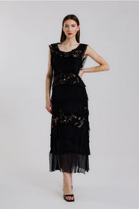 Elegant woman in a sleeveless black embroidered maxi dress with floral details, standing confidently