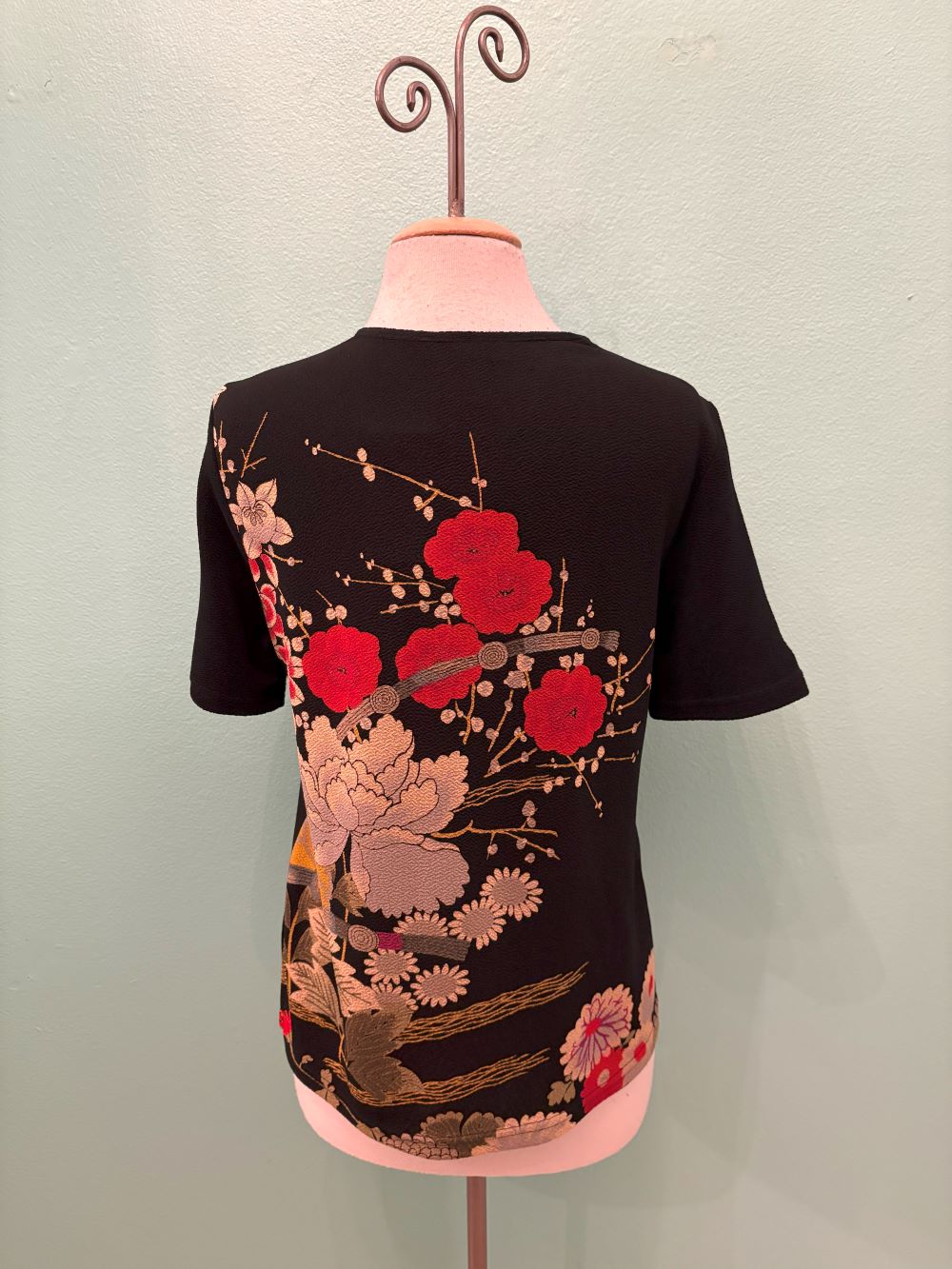 Back view of black kimono-style top with vibrant red and gold floral embroidery