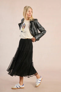 Woman in black mesh midi skirt, graphic tee, and leather jacket for a trendy look