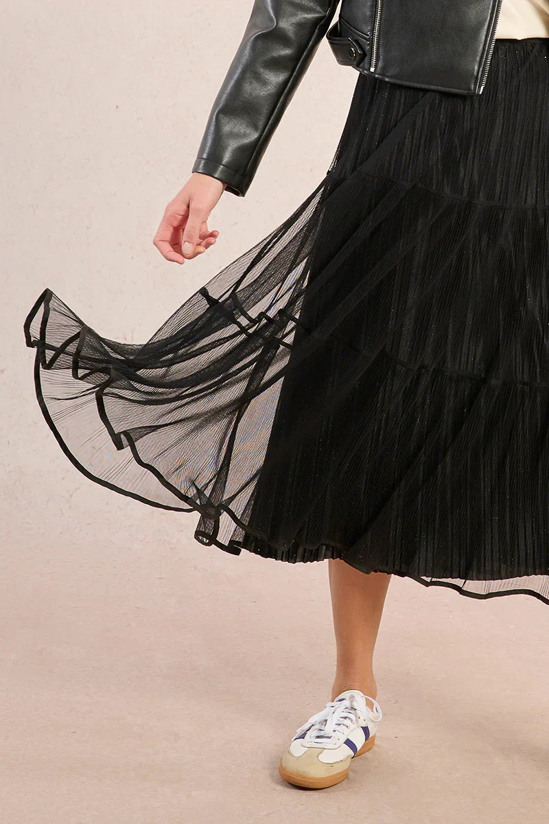 Model twirling in a black mesh tiered midi skirt with leather jacket and sneakers