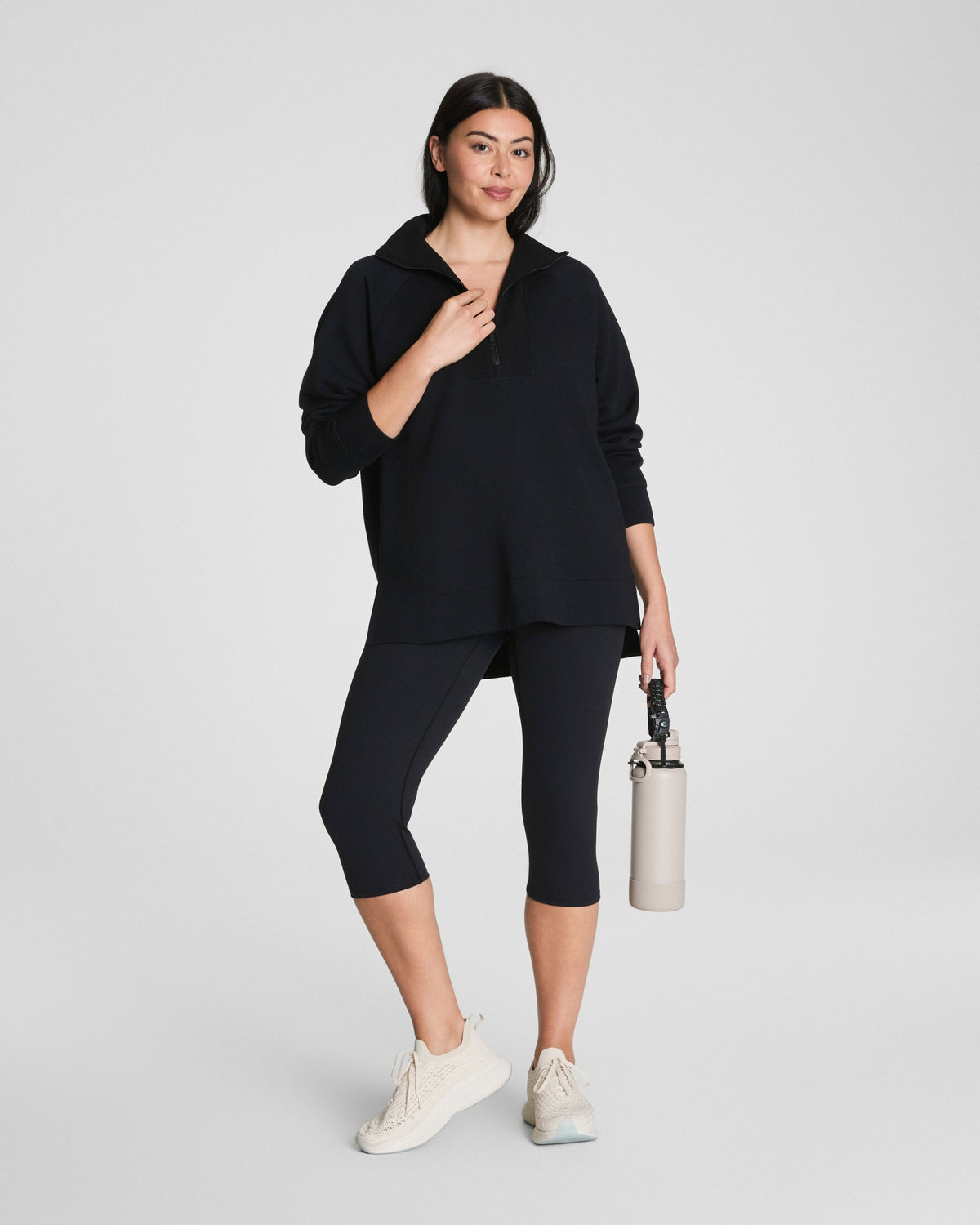 Woman in black quarter-zip pullover, arms crossed, showing relaxed fit