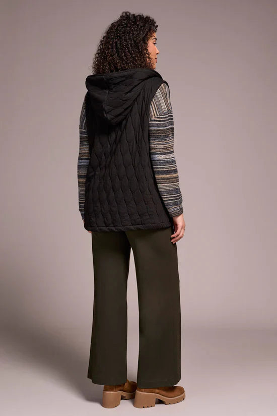 Back view of woman wearing a black quilted hooded vest with striped sleeves