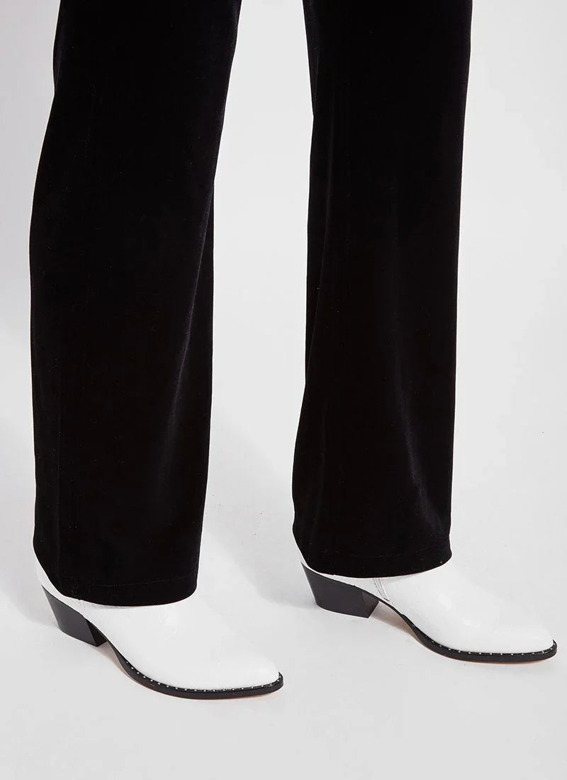 Close-up of black velvet trousers paired with white heeled boots