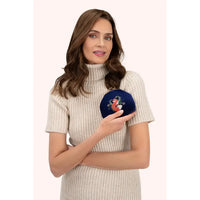 Woman holding blue velvet coin purse featuring an embroidered fox