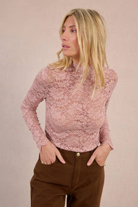 Front view of a woman wearing a blush floral lace mock neck blouse