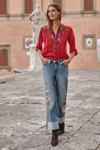 Woman walking in embroidered wide-leg denim jeans and red top, accessorized with necklaces outdoors