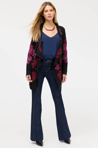 Woman wearing black open-front cardigan with magenta and purple floral embroidery, paired with blue tank and jeans