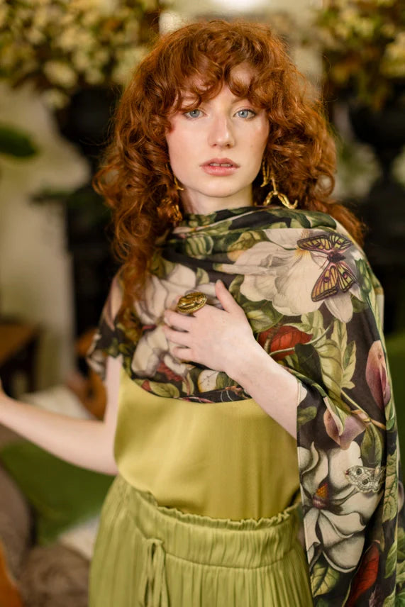 Woman wearing a lightweight scarf with a botanical and butterfly print, paired with a green dress
