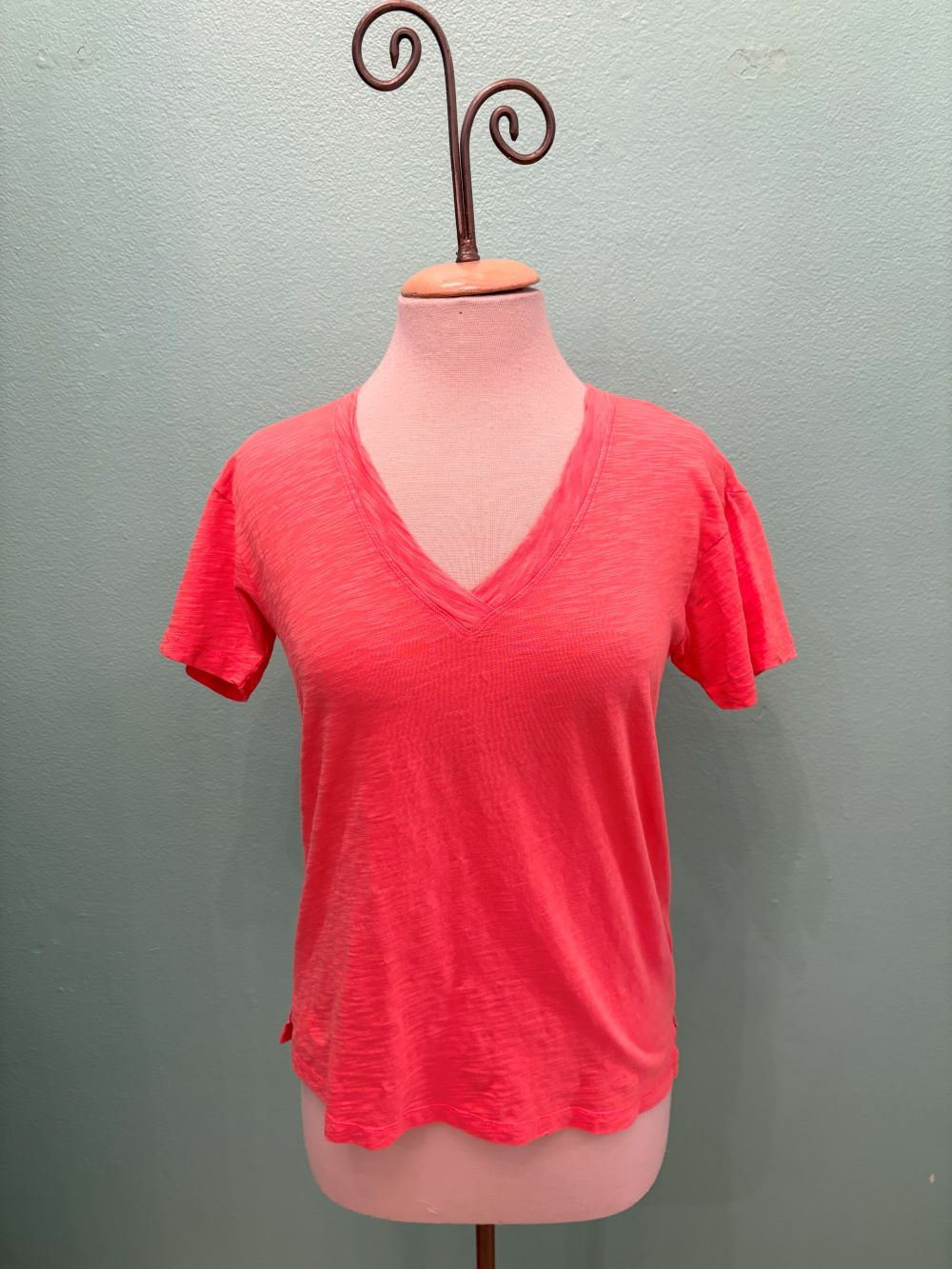 Front view of a bright coral V-neck t-shirt displayed on a mannequin