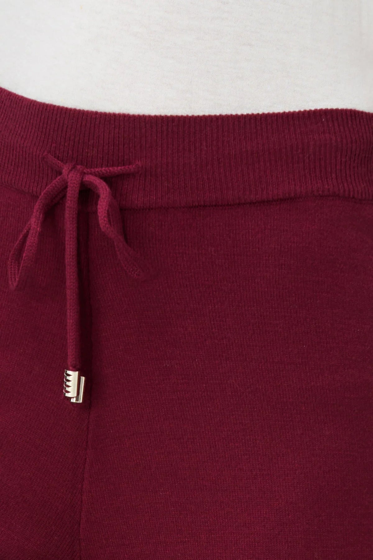 Close-up of burgundy knit jogger pants waistband with drawstring detail