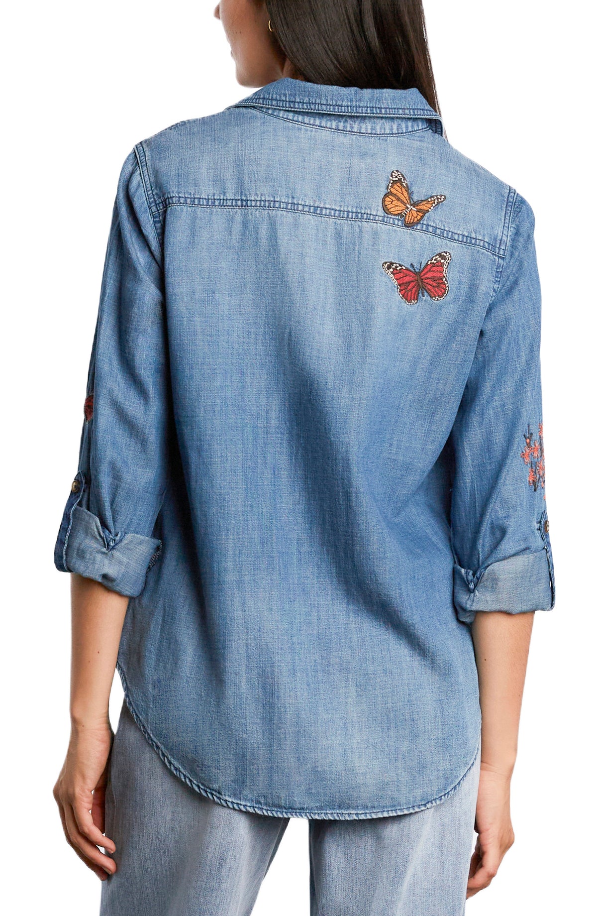 Back view of denim shirt featuring butterfly embroidery on the upper back and rolled sleeves