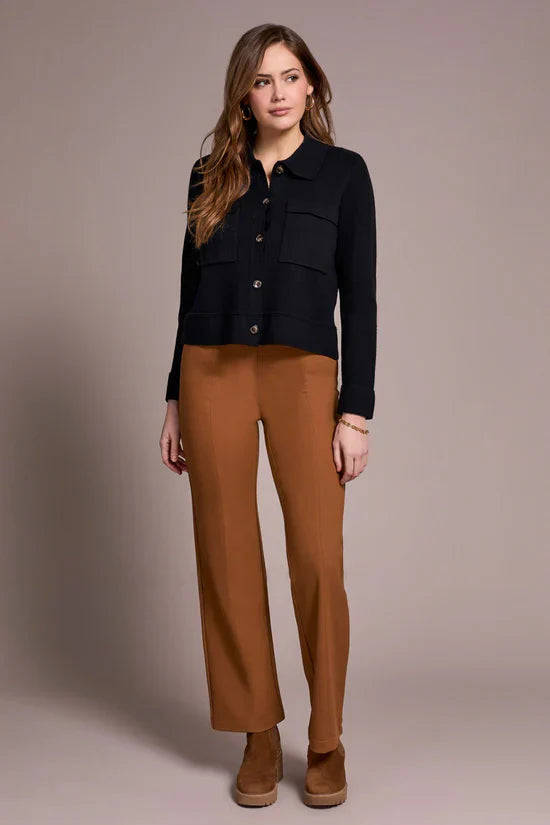 Front view of woman in caramel straight-leg pants styled with black button-up sweater and brown boots