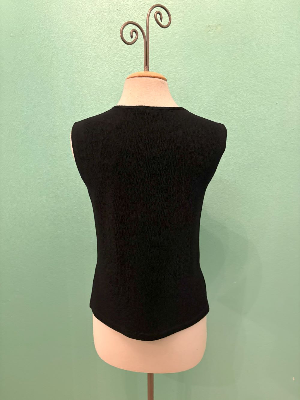 Back view of a classic black sleeveless knit top on a dress form