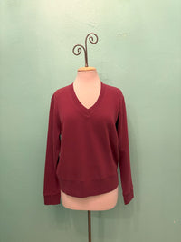 Front view of a burgundy V-neck sweatshirt displayed on a mannequin
