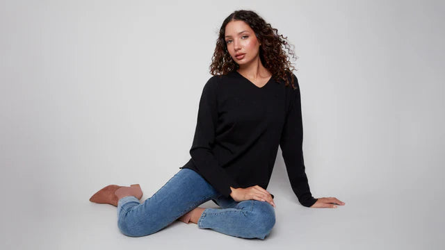 Woman posing in a classic black V-neck sweater and blue jeans