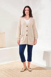 Model wearing classic cropped dark wash jeans with a beige cardigan and gold flats
