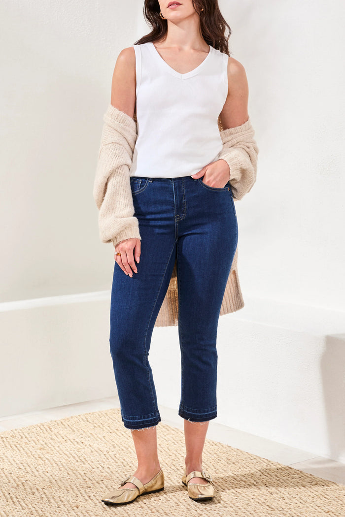 Closeup of classic cropped dark wash jeans paired with a white sleeveless top