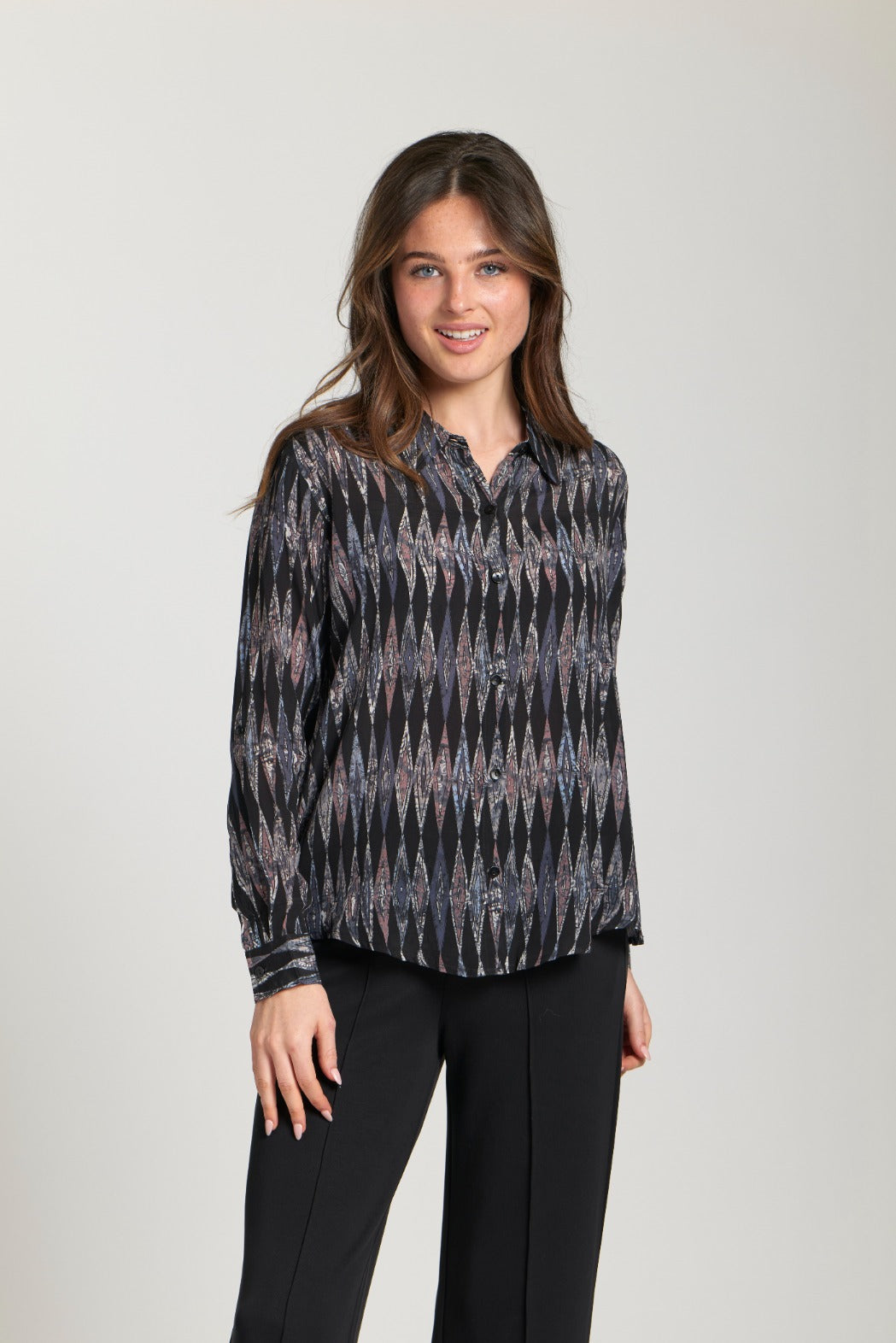 Close-up of a woman wearing a black blouse with shimmering geometric diamond pattern