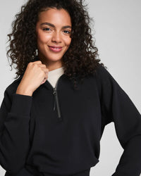 Woman smiling in a black half-zip pullover, close-up of the upper body