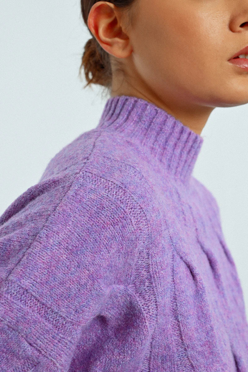 Close-up view of the lilac cable knit sweater fabric and high neckline
