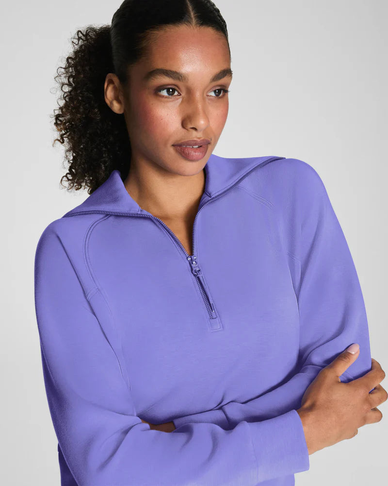 Close-up of a woman wearing a violet half-zip athletic jacket